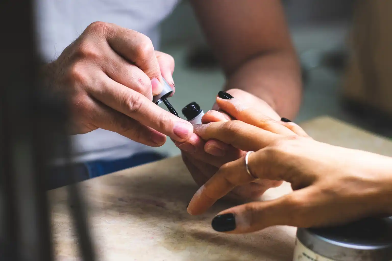Professional applying gel polish to a client's short natural nails