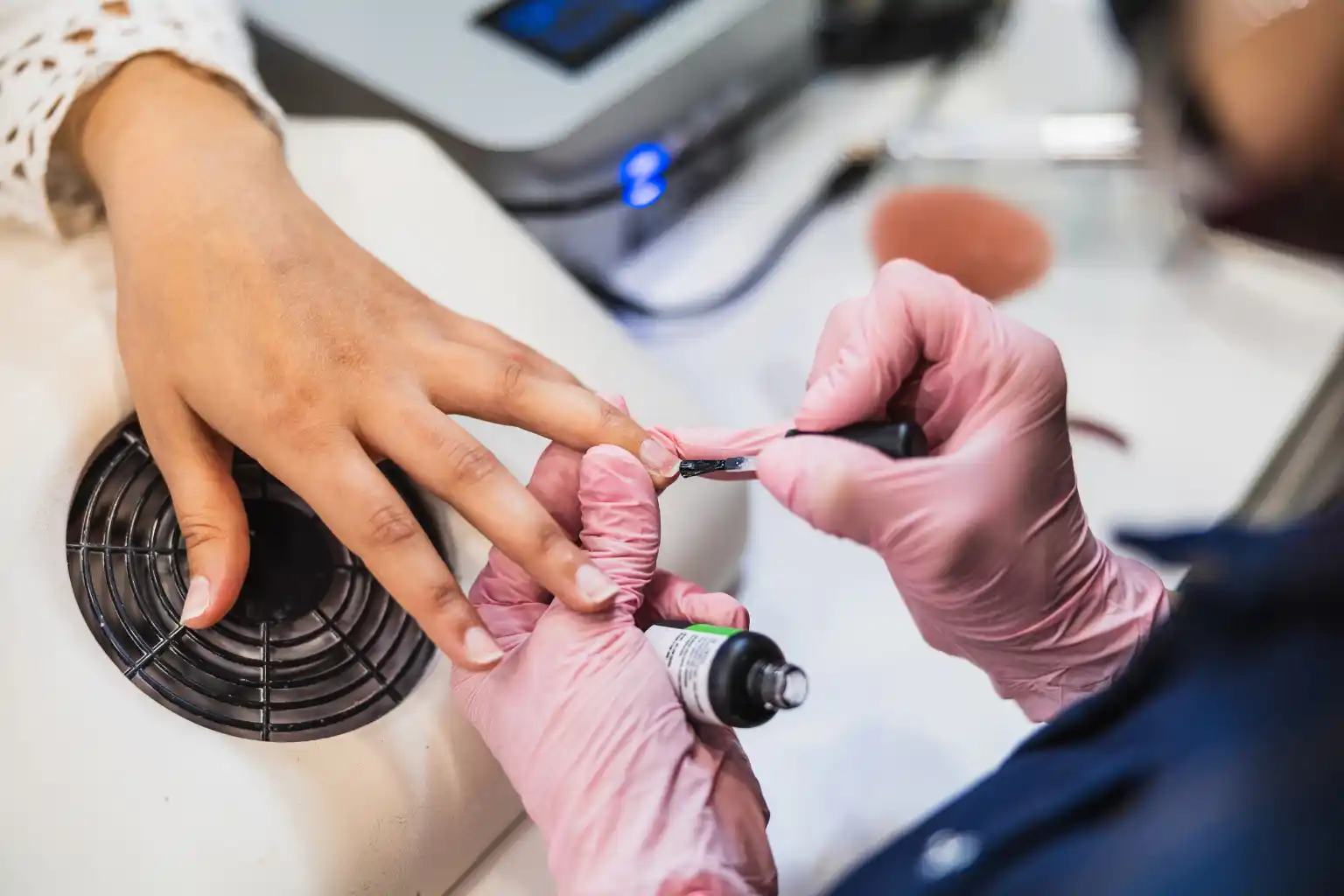 Nail technician applying a thin coat during a professional gel manicure