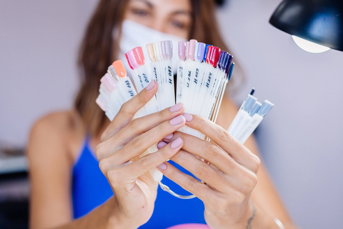 Nail technician comparing a fan of polish color samples